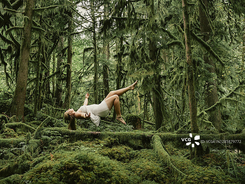 年轻女子身穿白裙漂浮在茂盛的海岸雨林中的合成照片图片素材