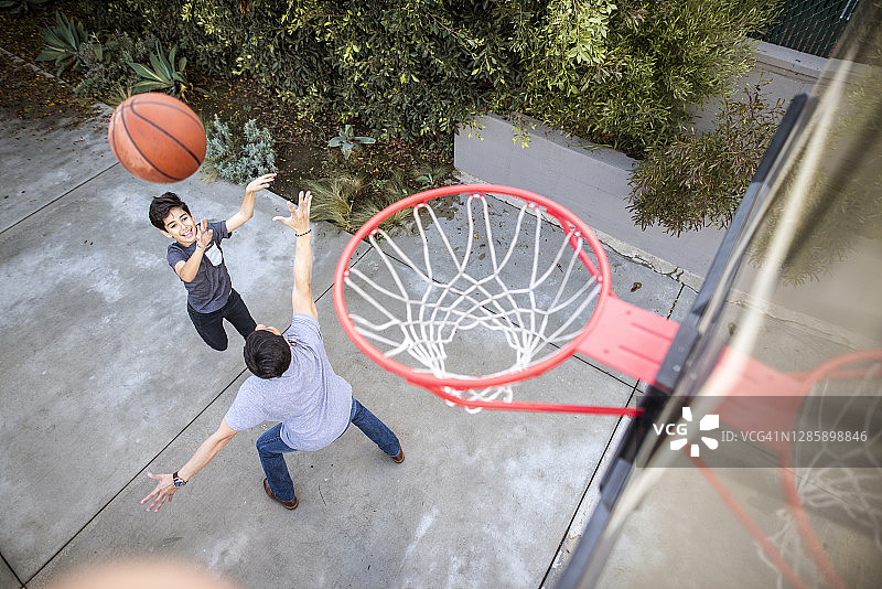 儿子在户外向篮球框投球图片素材