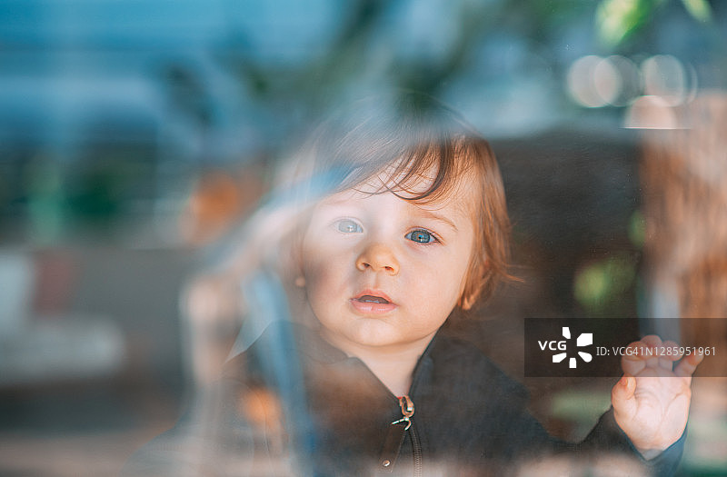 在窗户后面摆姿势拍照的可爱男婴图片素材