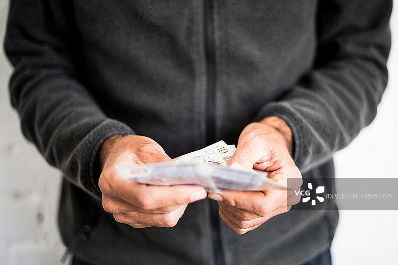 男子拿着五英镑和十英镑的纸币图片素材
