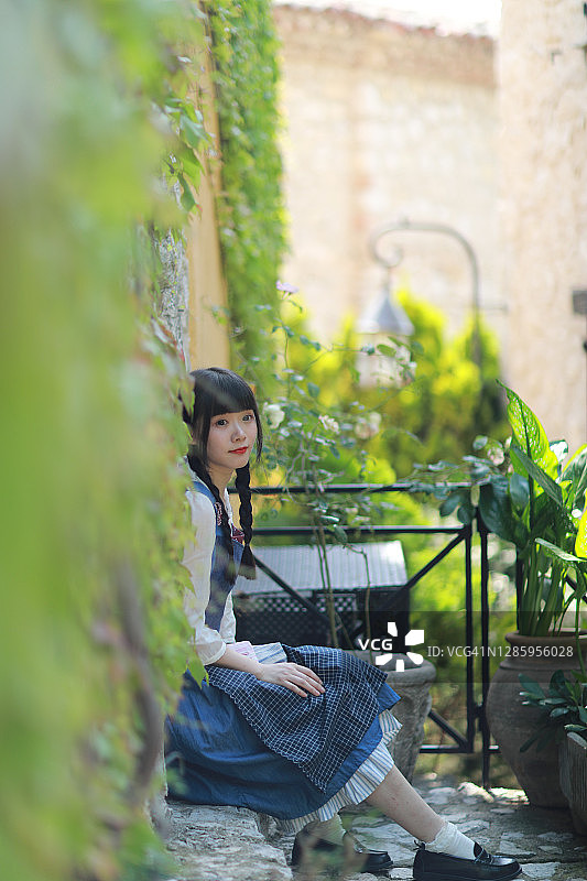 身穿蓝色复古连衣裙的中国女人在法国埃兹旅行图片素材