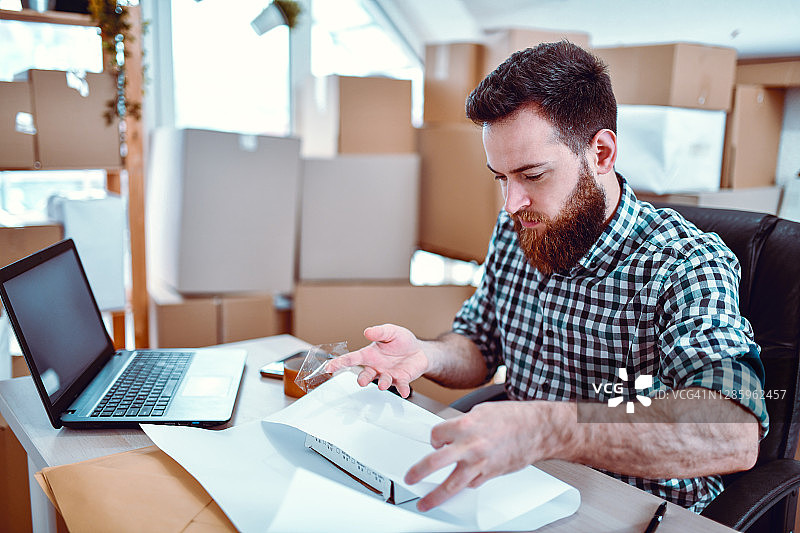 络腮胡男快递员用纸包装包裹图片素材