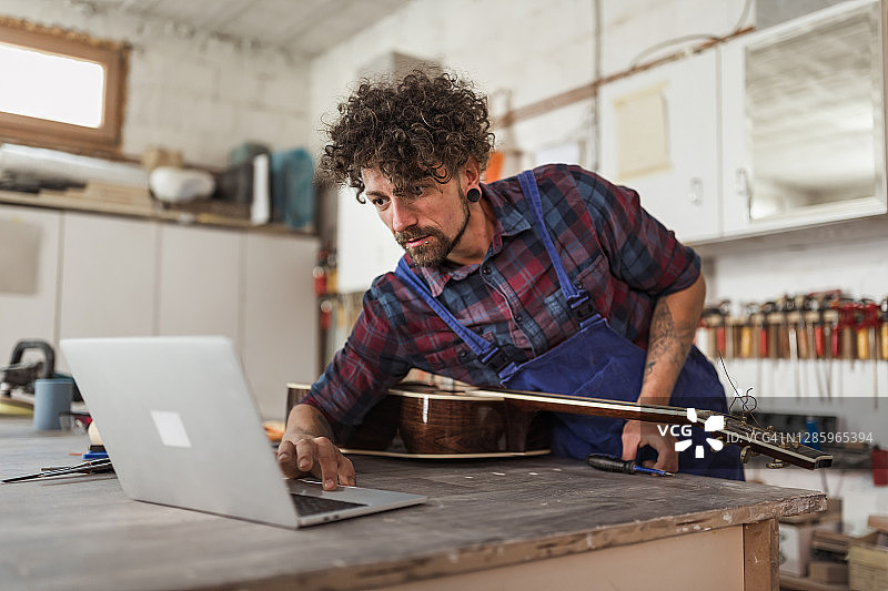 工人在他的工作室修理原声吉他图片素材