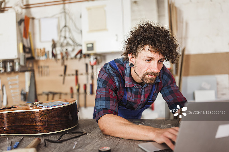 工人在他的工作室修理原声吉他图片素材