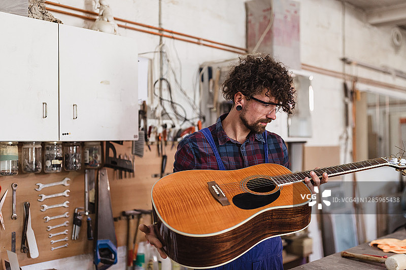 工人在他的工作室修理原声吉他图片素材