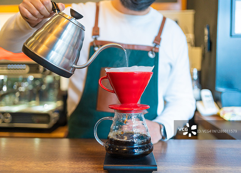 专业咖啡师在现代咖啡馆的木制柜台上用滤纸冲泡咖啡图片素材