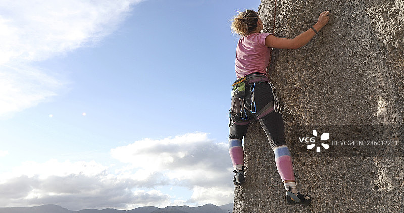 年轻女人攀登陡峭的岩壁图片素材