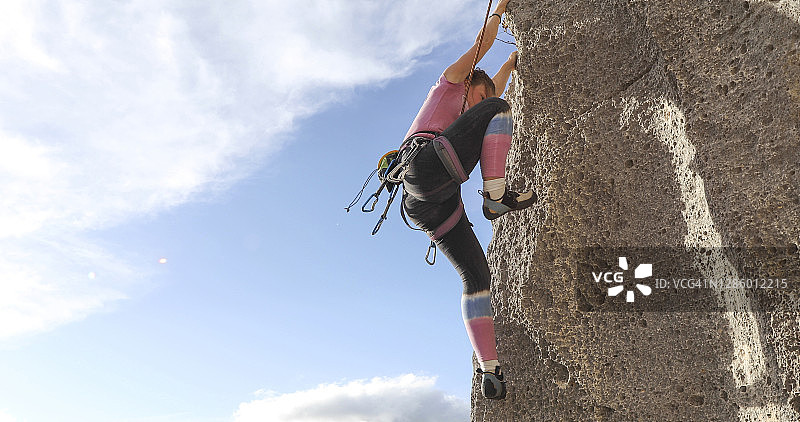 年轻女人攀登陡峭的岩壁图片素材