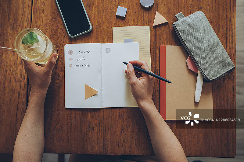 女学生在咖啡馆喝柠檬水时在笔记本上写励志笔记图片素材