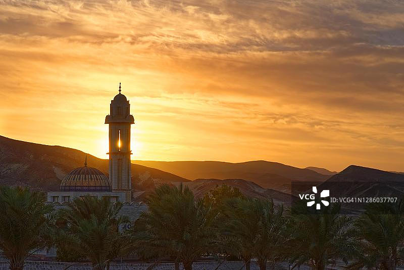 埃及马尔萨阿拉姆，马利基亚度假村阿布达巴巴，希尔顿努比亚度假村日落时分的棕榈树清真寺图片素材