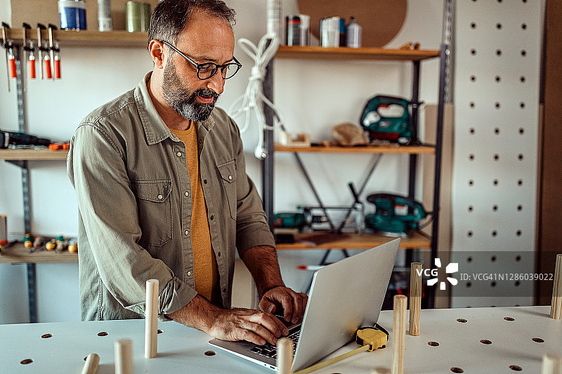 中年男人在家里的工作室使用笔记本电脑图片素材