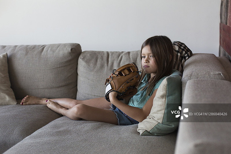 女孩坐在沙发上戴着棒球手套图片素材