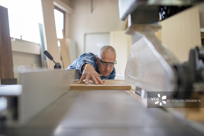 专注的木匠使用圆锯切割中密度纤维板图片素材