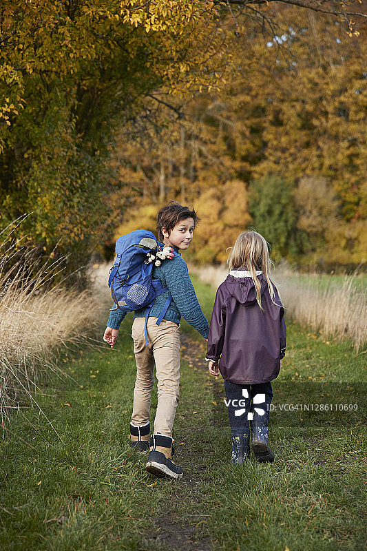 男孩和妹妹一起走着回头看图片素材