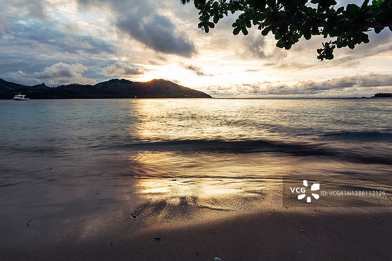 日落时分平静的海面，背景是热带岛屿图片素材