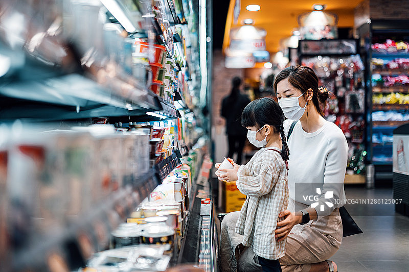 亚洲母女戴口罩在超市冷藏区购买有机乳制品图片素材