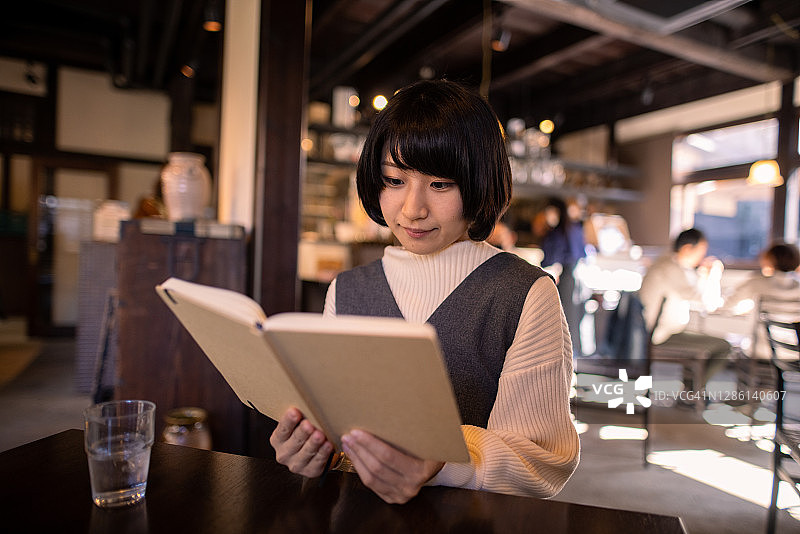 年轻女人在日式老餐馆里读书图片素材