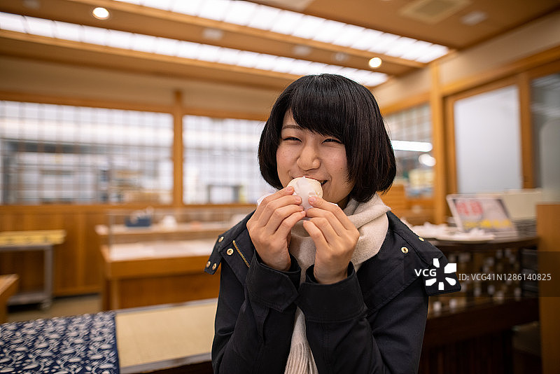 快乐的年轻女人吃日式温泉馒头图片素材