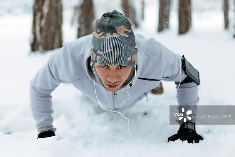 年轻男人在雪地里做俯卧撑图片素材