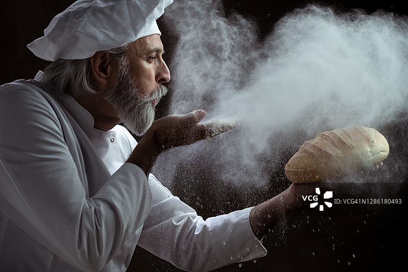 面包师在面包上吹面粉的侧面图片素材