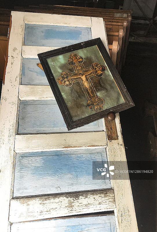 废弃教堂里被踢开的门上放着带框的宗教印刷品图片素材