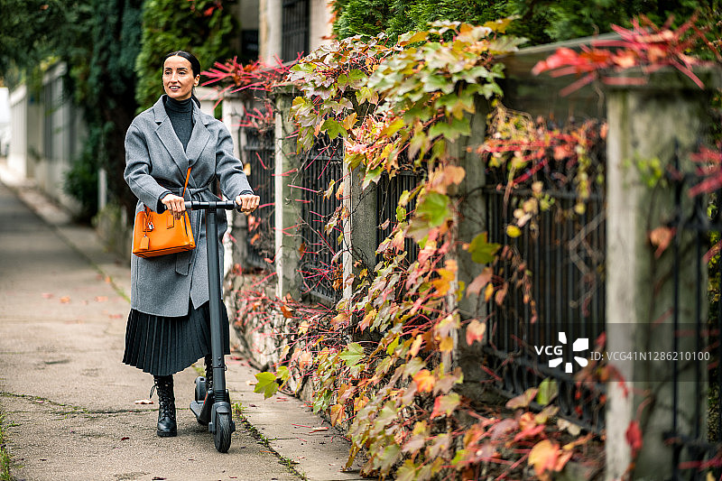 骑着电动滑板车上班的现代女商人图片素材