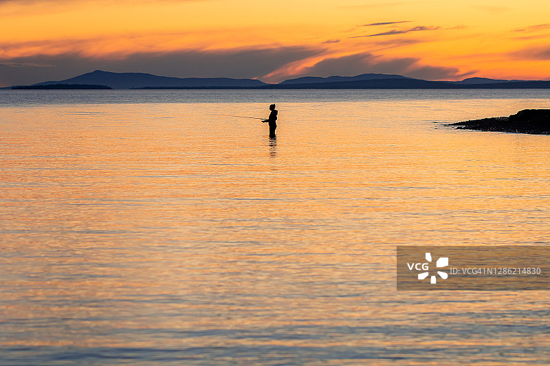 渔妇在卡累利阿平静的湖面上用旋转杆钓鱼图片素材