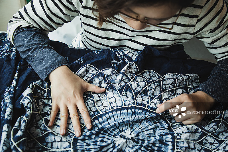 亚洲女性检查她的扎染作品图片素材