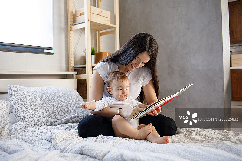 细心的母亲给可爱的儿子展示书中的图片图片素材