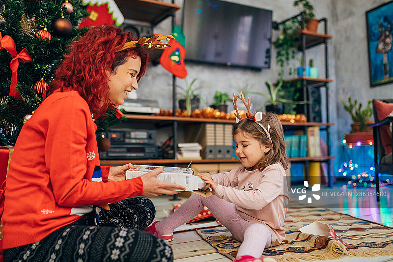快乐的幼儿兴奋地打开她的圣诞礼物图片素材