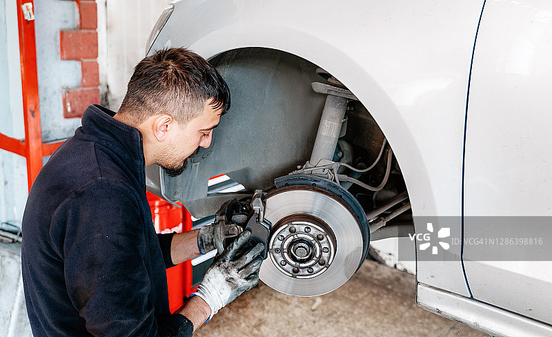 汽车修理工在车库更换刹车片图片素材