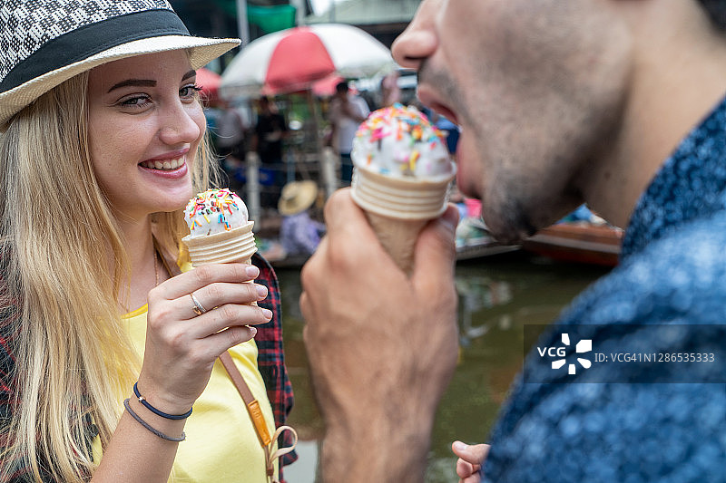 快乐的旅行夫妇在水上市场吃冰淇淋图片素材
