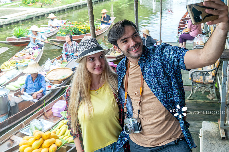 外国游客夫妇在丹嫩沙多水上市场用相机拍摄传统市场景观图片素材