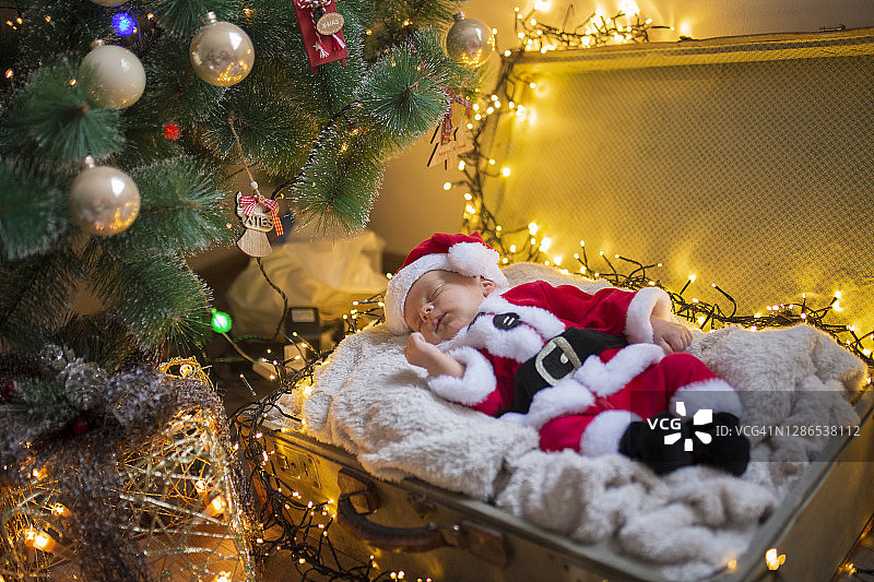 圣诞树下躺在行李箱里的男婴图片素材