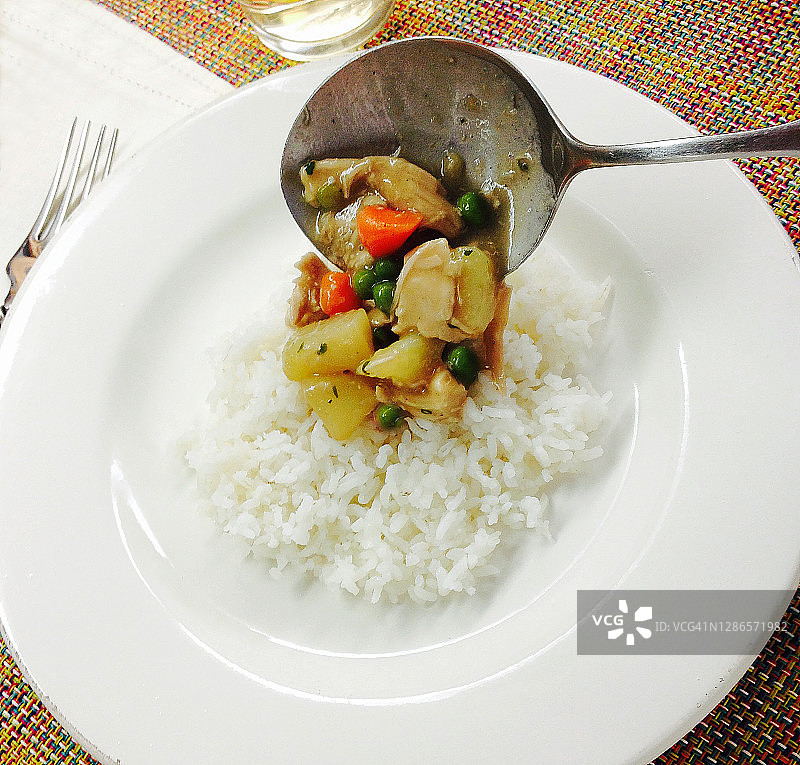 用勺子将法式奶油鸡肉或炖肉舀到长粒白米饭上图片素材