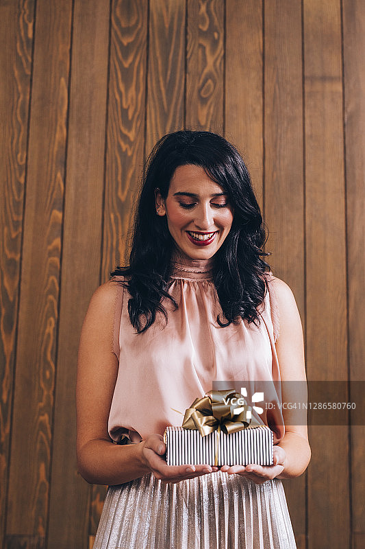 一位兴奋地拿着可爱生日礼物的年轻黑发美女的肖像图片素材