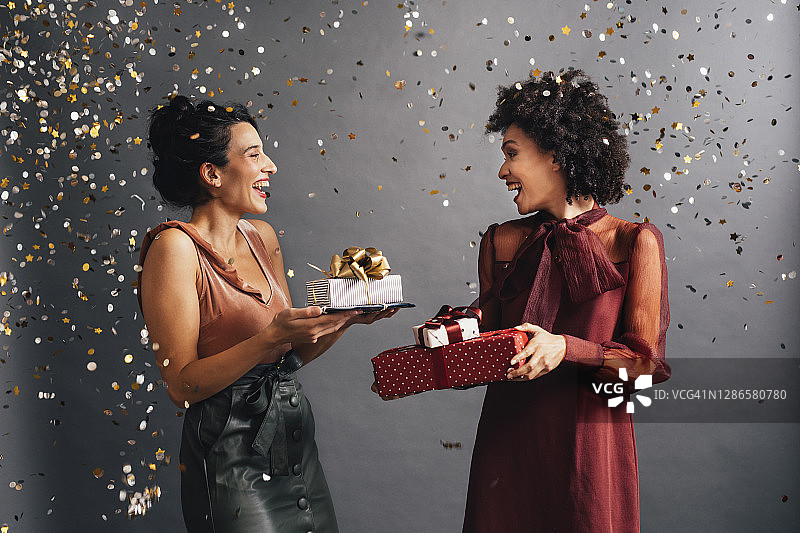 圣诞派对互赠礼物的优雅女士与飞舞的彩屑图片素材