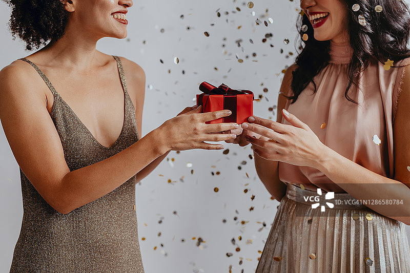 圣诞快乐：派对上互赠圣诞礼物的微笑年轻女性特写图片素材