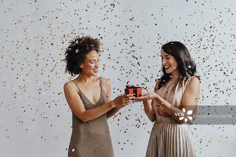 圣诞节：两个年轻女子在派对上交换圣诞礼物图片素材