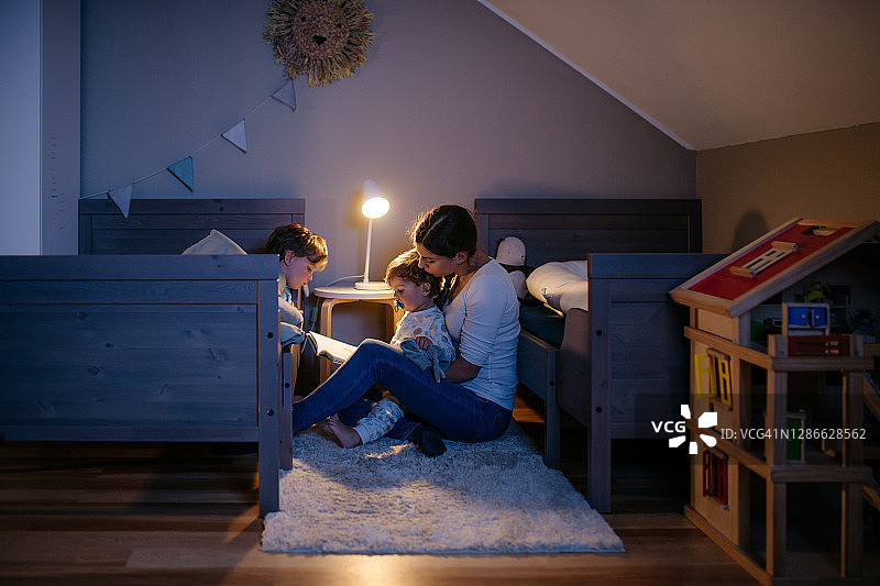 母亲给她的两个孩子读童话书图片素材