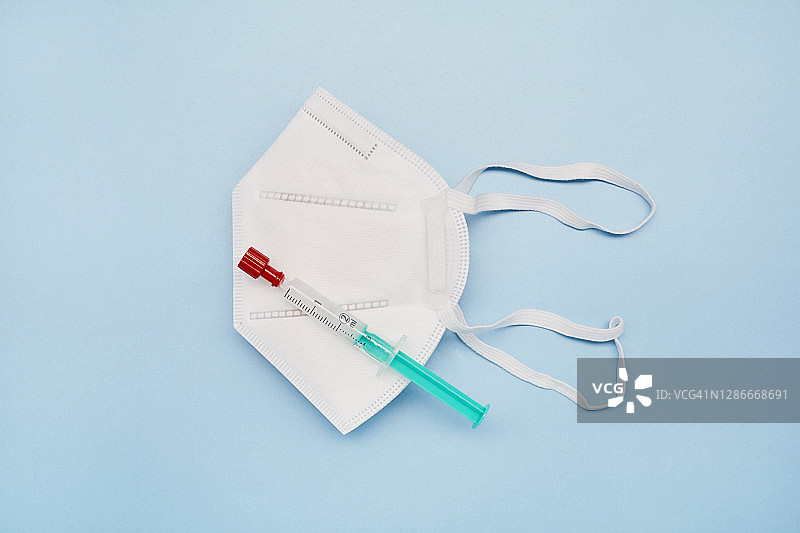 蓝色背景上的FFP2口罩和注射器图片素材