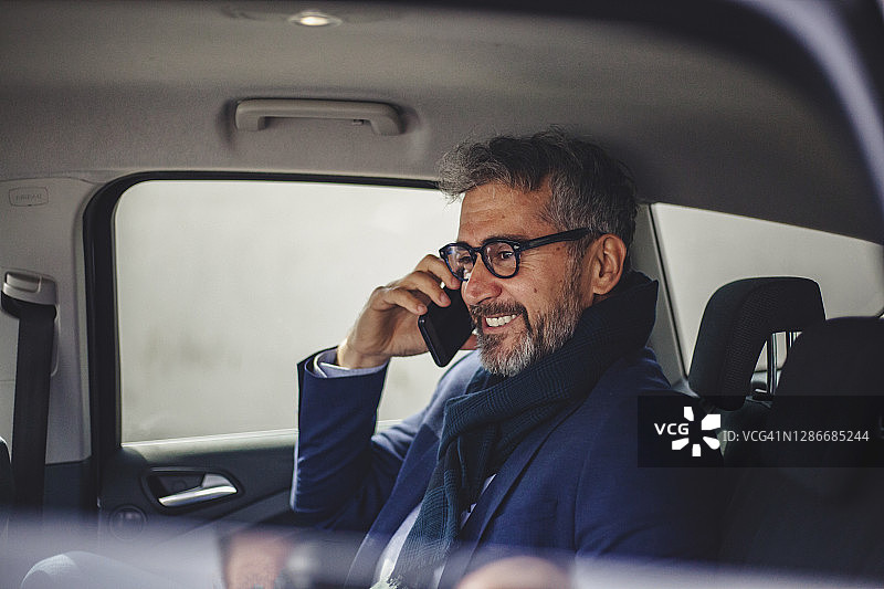车内的资深商人——一位年长的商人在汽车后座打电话图片素材