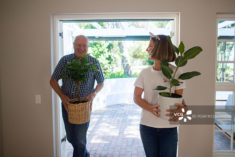 父亲帮助女儿一起搬运植物到她的新公寓图片素材
