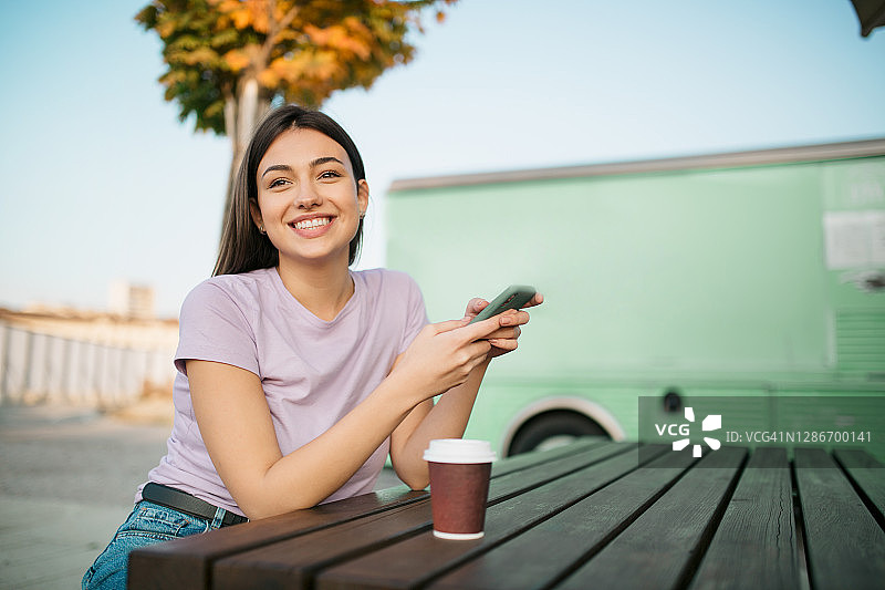 快乐的年轻白人女性使用智能手机图片素材