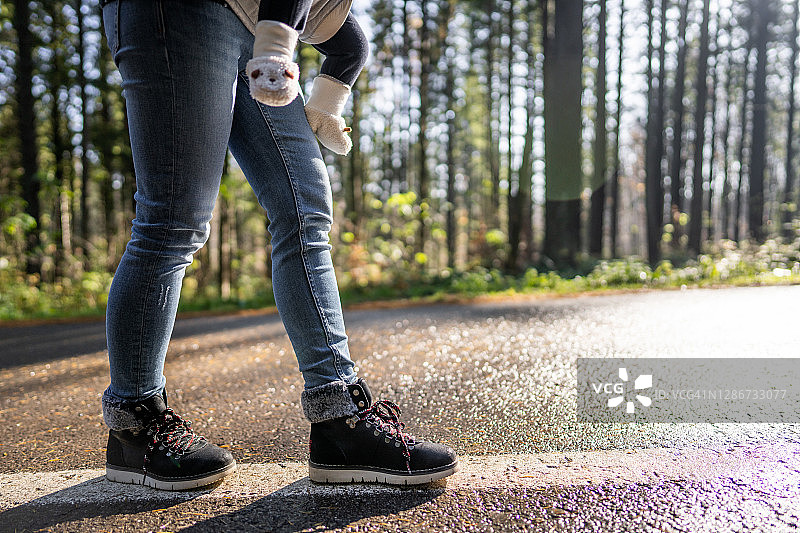 年轻母亲抱着她的宝宝站在大自然的道路上图片素材