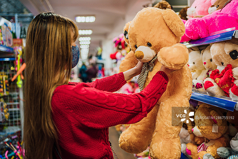 女人在玩具店里挑选泰迪熊图片素材