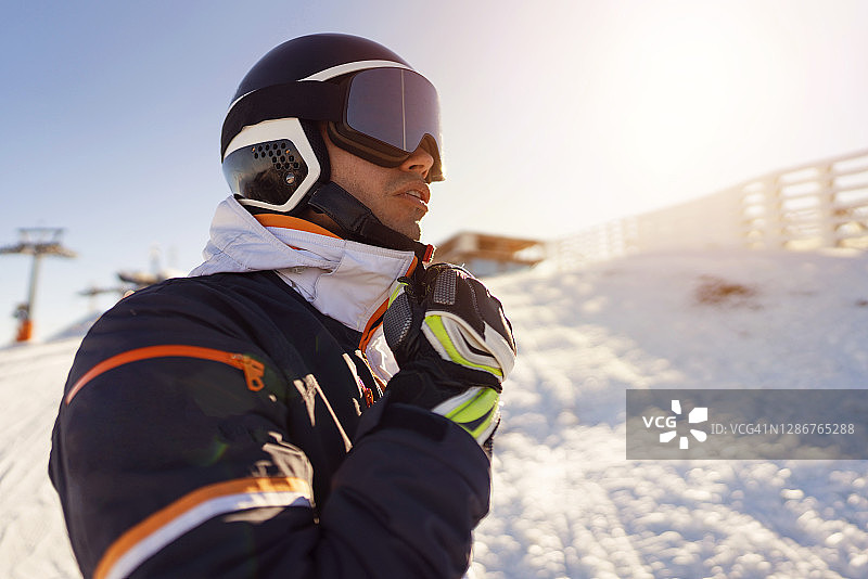 身穿全套滑雪装备、正在系外套的年轻男子特写图片素材