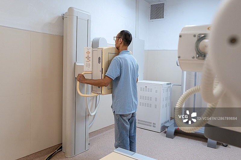 亚洲男性患者使用X光机进行体检图片素材