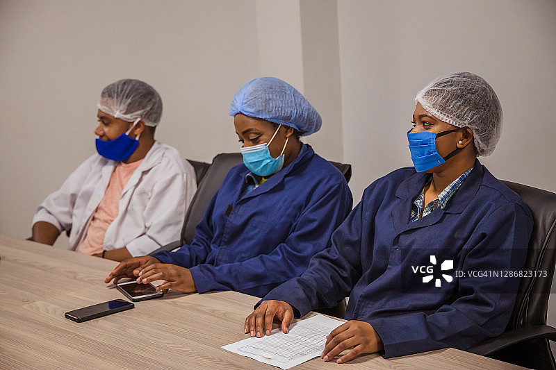 非洲/赞比亚工厂工人在会议室戴着口罩，在疫情期间开会图片素材