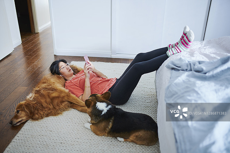 在卧室地板上与狗一起放松的女人图片素材